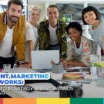 Diverse creative marketing team smiling around a desk with a laptop, symbolizing content marketing strategies that work.