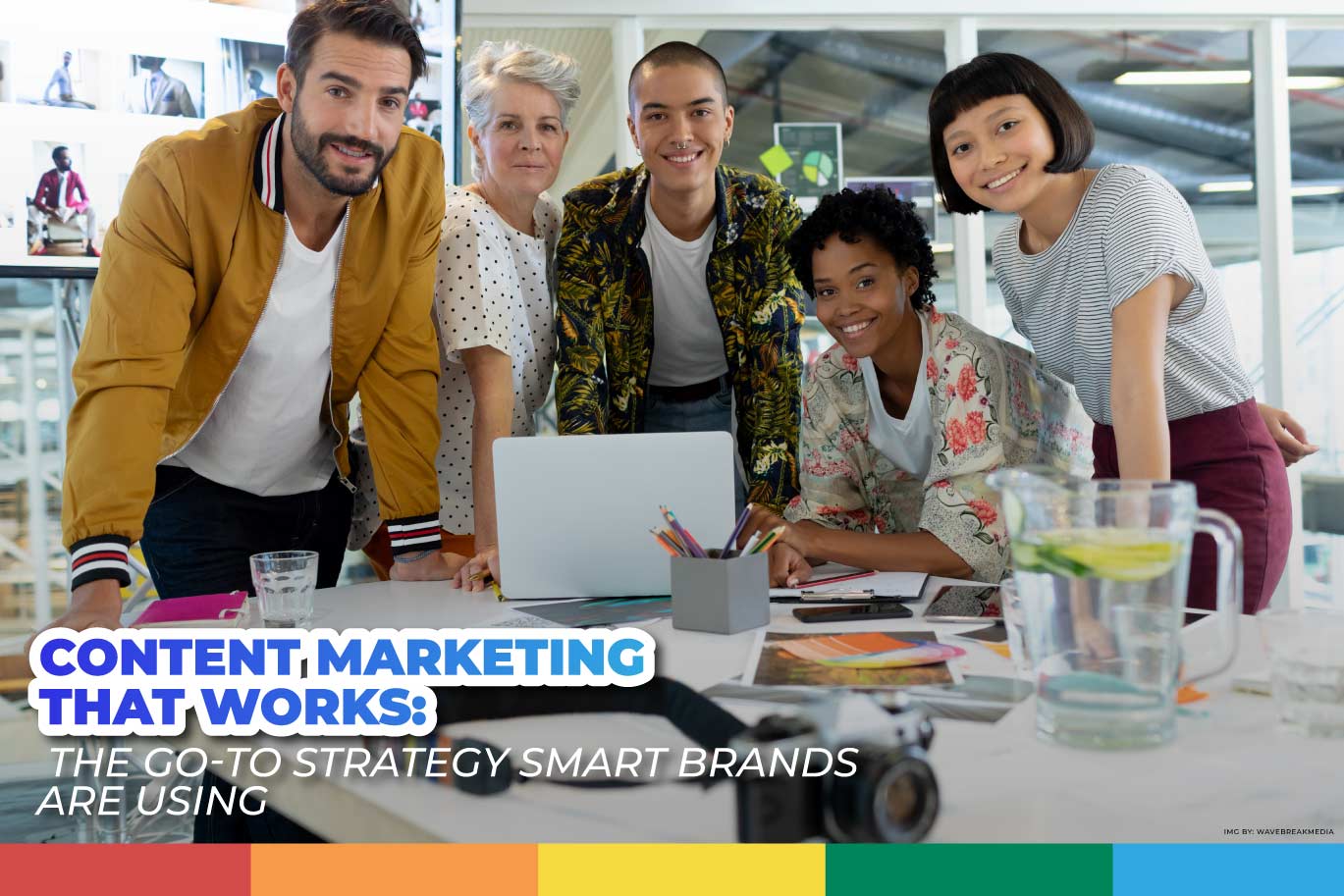 Diverse creative marketing team smiling around a desk with a laptop, symbolizing content marketing strategies that work.